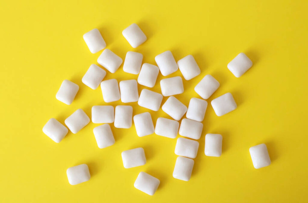 White chewing gum on a yellow background. Chewing pads scattered a lot, top view. - Φωτογραφία, εικόνα