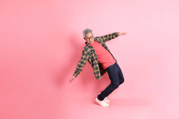 The full length of senior Asian man standing on the pink background. - Фото, изображение