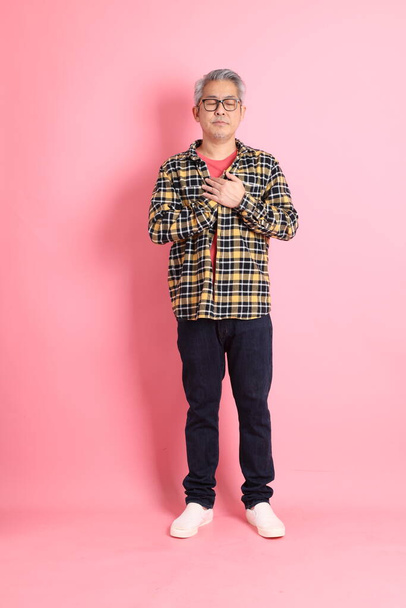 The full length of senior Asian man standing on the pink background. - Zdjęcie, obraz