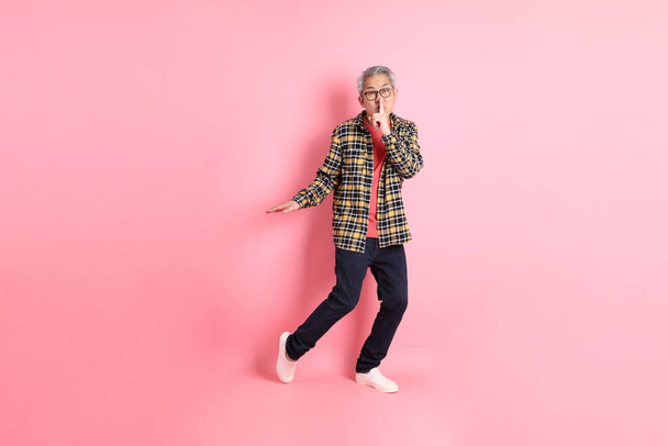 The full length of senior Asian man standing on the pink background. - Photo, Image