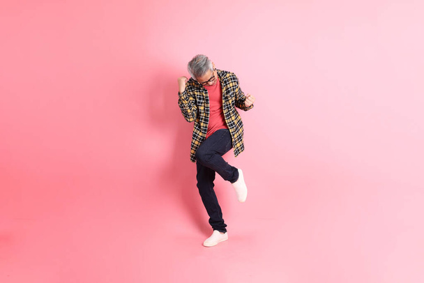 The full length of senior Asian man standing on the pink background. - Foto, immagini