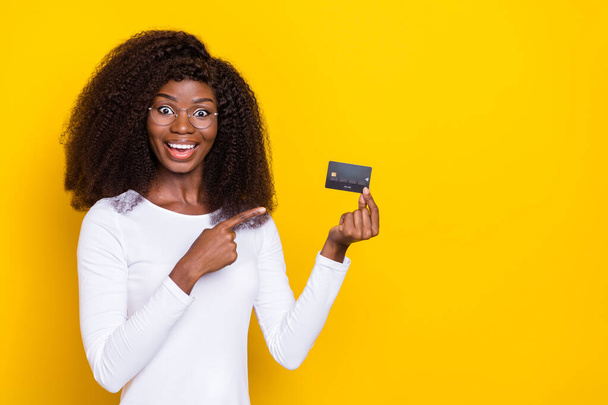 Portrait of excited attractive person indicate finger hand hold plastic debit card isolated on yellow color background. - Foto, Imagem