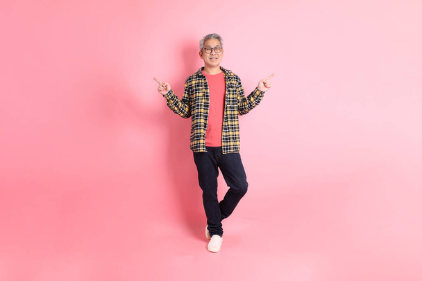 The full length of senior Asian man standing on the pink background. - Photo, Image