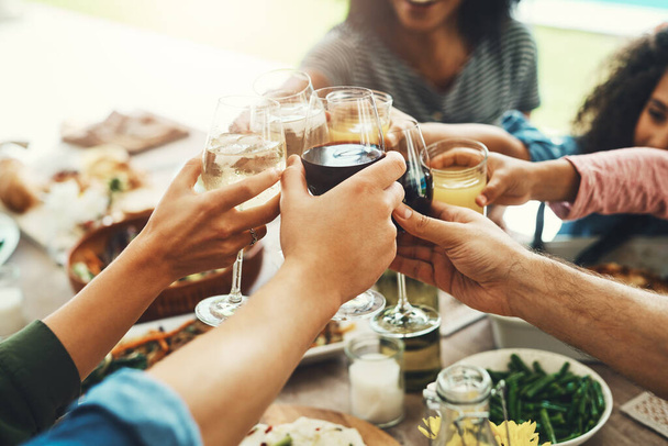 Beve a tutti. un gruppo di persone irriconoscibili che uniscono i loro bicchieri insieme per un brindisi mentre si godono un pasto insieme all'aperto - Foto, immagini