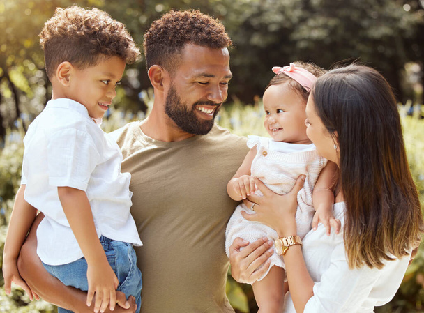 Black family, happy and nature park with people holding a child and baby outdoor. Mother, father and children together in the summer sun with happiness smile and kids spending quality time outdoors. - Photo, Image
