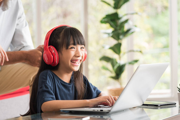 Щаслива дочка сидить і робить домашнє завдання і вчиться онлайн з сім'єю вдома
. - Фото, зображення