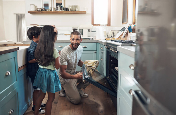 A volte devi solo cuocere. un giovane uomo che cuoce a casa con i suoi due bambini - Foto, immagini