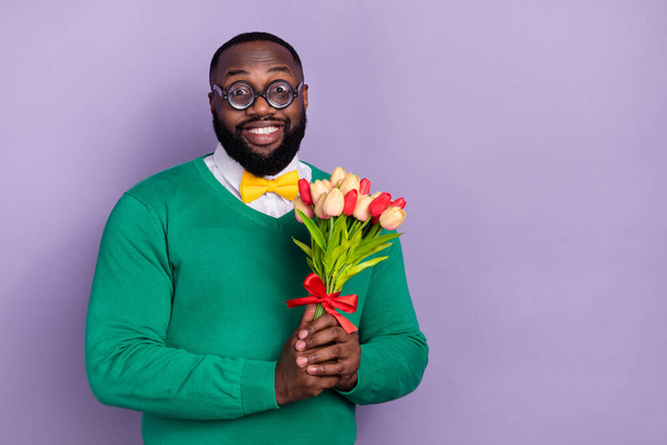 Portré vicces pozitív ember tartsa friss virágok fogas mosoly üres hely hirdetés elszigetelt lila színű háttér. - Fotó, kép