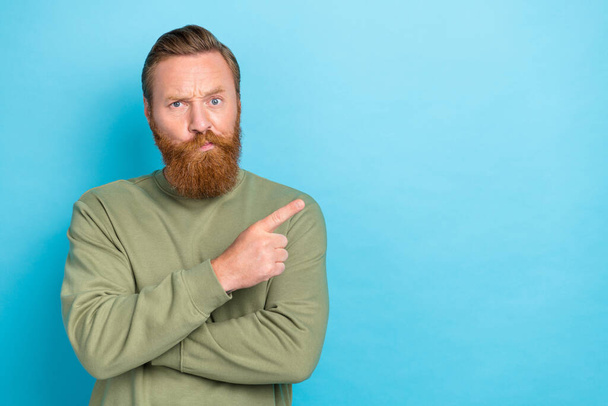 Portrait of thoughtful minded guy with ginger hairdo wear khaki pullover indicating empty space isolated on turquoise color background. - Photo, image