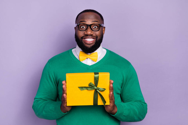 Portrait of positive crazy man hold desirable giftbox toothy smile isolated on purple color background. - Zdjęcie, obraz
