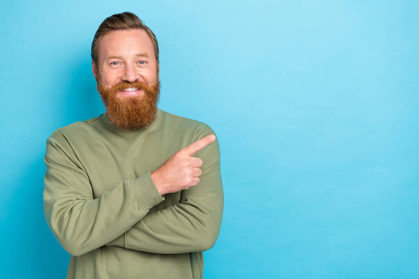 Portrait of good mood handsome guy with ginger hairdo wear khaki pullover indicating empty space isolated on turquoise color background. - Foto, afbeelding