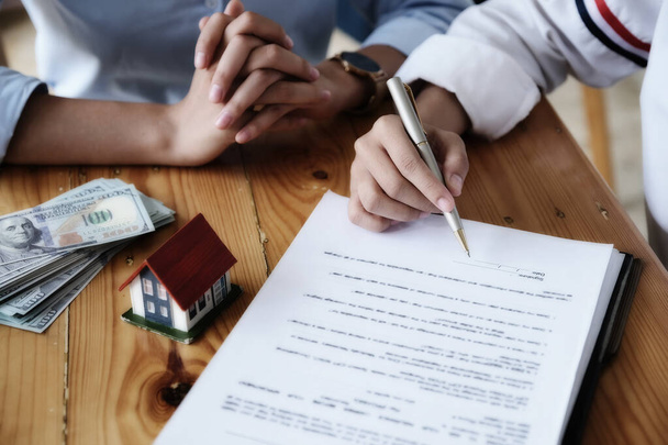 Der Kunde hält einen Stift in der Hand und liest die Bedingungen, um mit dem Verkäufer einen Hauskaufvertrag mit Unterlagen über die Hausversicherung abzuschließen - Foto, Bild