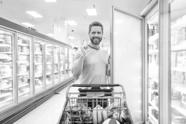 inspired with idea. customer consumer with purchases. guy at grocery store. shopper at groceries. buying food at supermarket. consumption. happy man with shopping cart. - Photo, Image