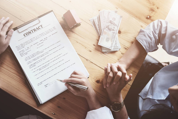 The customer holds a pen and reads the conditions in order to sign a house purchase contract with home insurance documents with the salesperson - Фото, зображення