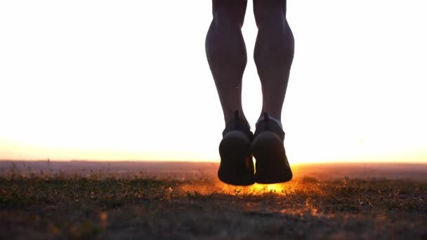 Ein muskulöser Mann springt bei Sonnenuntergang über das Seil auf dem Feld. Mittelschuss - Filmmaterial, Video