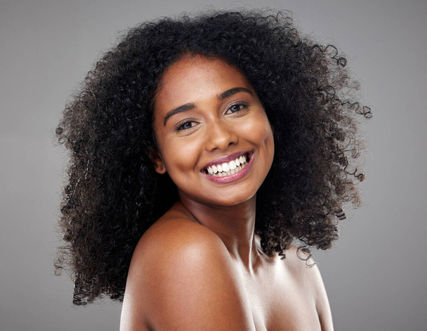 Black woman, makeup and beauty with hair, cosmetic and smile with afro, face and happiness. Model, happy and skincare with cosmetics, shine or glow on skin for hair care, wellness or health in studio. - Foto, Imagen