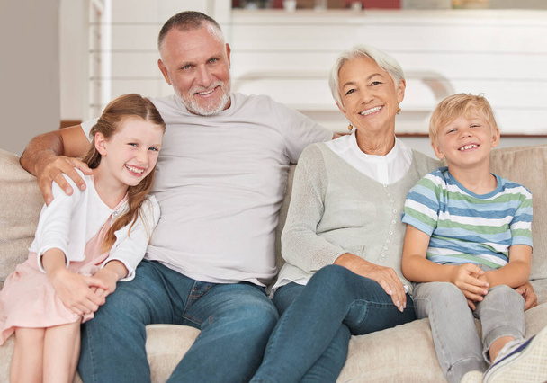 Nagyszülők, unokák és boldogok vagyunk, hogy együtt lehetünk és mosolyoghatunk a kanapén a nappaliban. Portré, nagyapa és nagymama unokák a szeretet, kötődés és a boldogság a kanapén, mint a család. - Fotó, kép