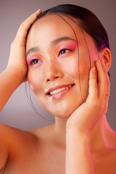 Schönheit, Make-up und Kosmetik eines koreanischen Models mit einem Lächeln. Kosmetik, glückliche und ruhige junge Person Gesicht posiert mit den Händen, um Haut Wohlbefinden zu zeigen, Hautpflege mit kreativem rosa Studiolicht. - Foto, Bild