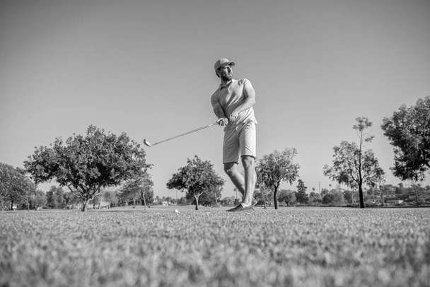 υγιής άνθρωπος παίζει παιχνίδι στο πράσινο γρασίδι. καλοκαιρινή δραστηριότητα. επαγγελματική υπαίθρια σπορ. Άντρας παίκτης του γκολφ σε επαγγελματικό γήπεδο γκολφ. πορτρέτο του παίκτη του γκολφ στο καπέλο με μπαστούνι του γκολφ. τρόπος ζωής των ανθρώπων. - Φωτογραφία, εικόνα
