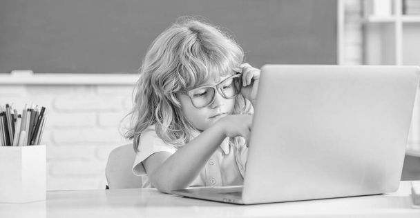 busy kid boy in glasses study online in school classrrom with computer, school. - Foto, Imagen