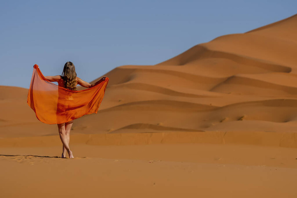 Ένα όμορφο μοντέλο θέτει γυμνό ενάντια στους αμμόλοφους στη μεγάλη έρημο Σαχάρα στο Μαρόκο - Φωτογραφία, εικόνα
