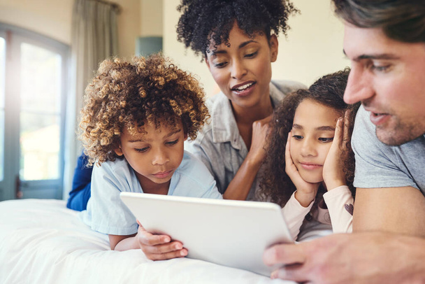Technologia bawi ich ciekawe umysły. rodzina korzystająca z tabletu cyfrowego razem w domu - Zdjęcie, obraz