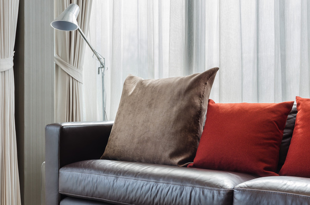 almohada marrón y roja en sofá moderno con lámpara
 - Foto, imagen