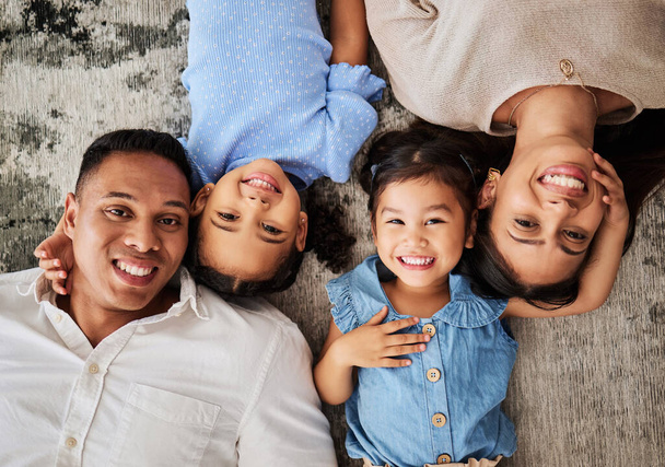 Happy family, love and portrait on floor by kids and parents bonding in living room from above. Face, family and girls smile, relax, and bond with mother and father, laughing and having fun on carpet. - Foto, immagini