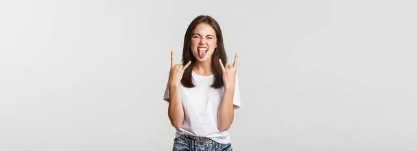 Joyful knap meisje tonen rock-on gebaar en genieten van concert. - Foto, afbeelding