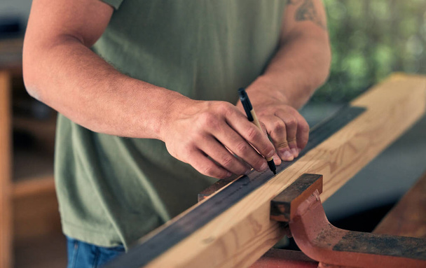 Человек плотник, измерить дерево для строительства и строительства проекта для профессионального ремонта дома. Разнорабочий, измеряющий деревянную балку и маркировку ручкой для оформления дома. - Фото, изображение