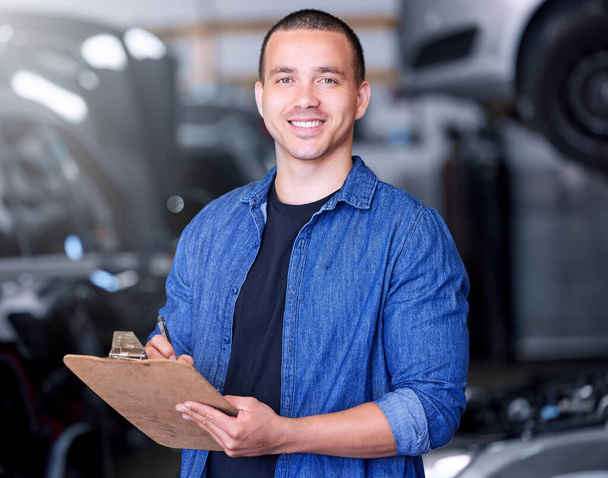 Man, clipboard writing and mechanical engineer in workshop, car manufacturing industry and car garage. Portrait, smile and happy motor production worker with repair schedule or export parts documents. - Fotografie, Obrázek