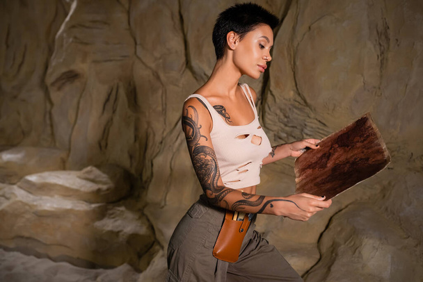 seksikäs arkeologi toppi tarkastellaan antiikin kartta lähellä rock autiomaassa - Valokuva, kuva