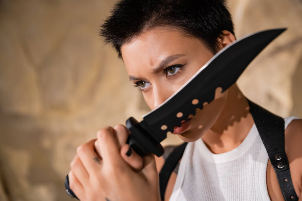 armed and sexy archaeologist with short hair holding sharp knife  - 写真・画像