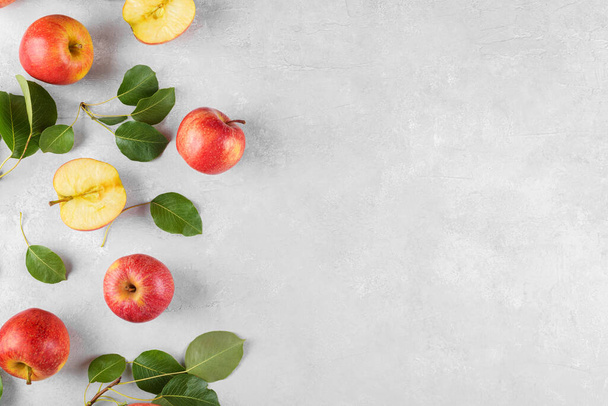 Reife rote frische Bio-Äpfel ganz und in Scheiben geschnitten mit grünen Blättern auf hellgrauem, konzentriertem Tischhintergrund. Apple Banner mit Platz für Ihren Text, Draufsicht, Flay - Foto, Bild