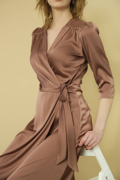 Serie of studio photos of young female model in brown silk satin wrap midi dress. - Zdjęcie, obraz