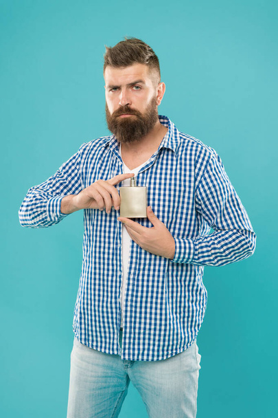 trendy caucasian guy with beard and mustache presenting male perfume on blue background, cosmetics. - Valokuva, kuva