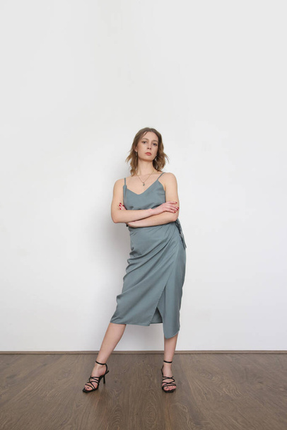 Female model wearing bluish grey camisole silk top and wrapped midi skirt. Stylish monochrome summer outfit. Fashion Studio shot. - Foto, afbeelding