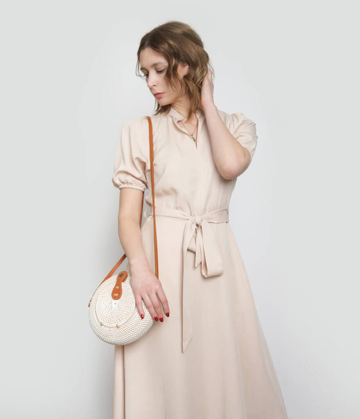 Studio shot van vrouw in stijlvolle eenvoudige beige viscose zomer jurk. - Foto, afbeelding