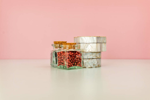 Skleněné nádoby s kořením a krabicemi od perel na neutrálním povrchu - Fotografie, Obrázek