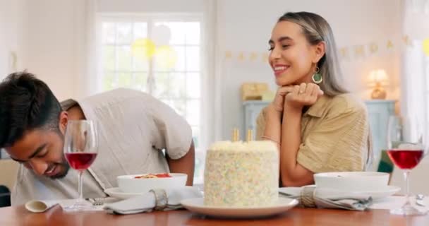 Interracial couple, gift and celebrate birthday being happy, kiss and smile in home at table with cake. Love, man and woman being content, romantic and present being cheerful celebration together - Footage, Video