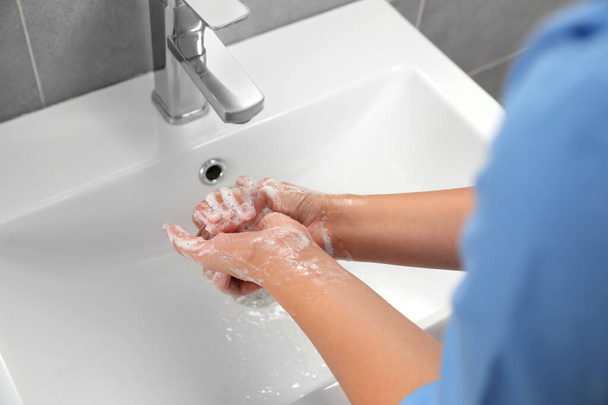 Doctor washing hands with water from tap in bathroom, closeup - Zdjęcie, obraz