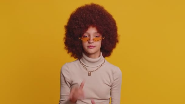 Gelukkig jong schoolmeisje met afro weelderige kapsel coiffure maken speelse grappige gekke gezichtsuitdrukkingen en grimmig, rommelen rond, tongzoenen. tiener vrouw kind kind op gele achtergrond - Video