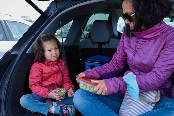 Mom and daughter having snacks in the back of an SUV - Photo, Image