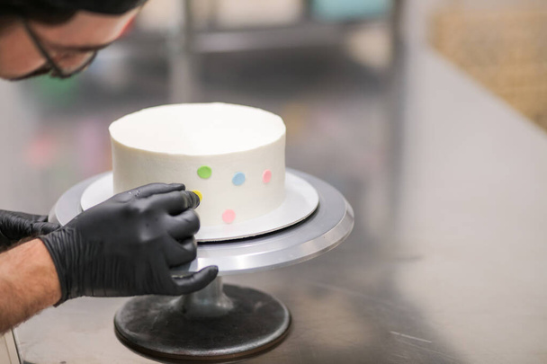 Donmuş bir fincan keki çok renkli noktalarla süslemek. - Fotoğraf, Görsel