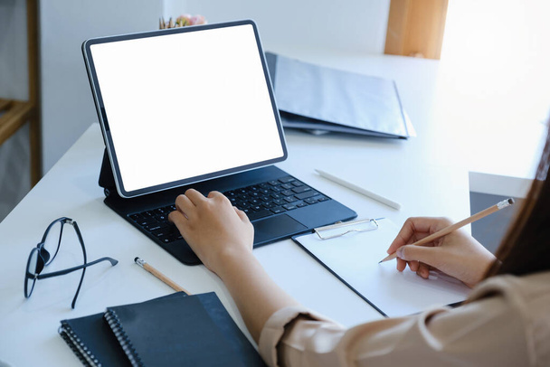 A woman using tablet with a blank white screen. The blank space on the white screen can be used to write a message or place an image. - Photo, image
