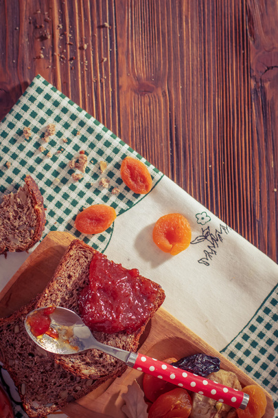 Wholemeal bread with apricot jam surrounded by dry fruit. - Photo, Image