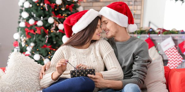 Amar jovem casal com presente de Natal em casa
 - Foto, Imagem