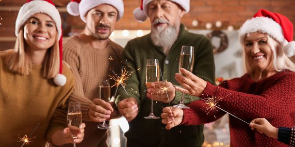 Gelukkige familie met kerst wonderkaarsen en glazen champagne thuis - Foto, afbeelding