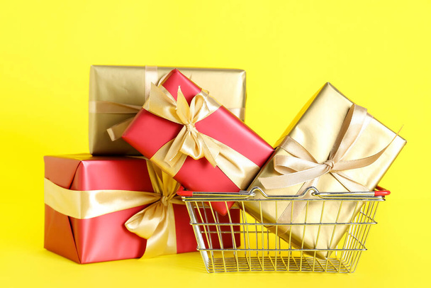 Shopping basket with gift boxes on yellow background. Black Friday sale - Foto, immagini