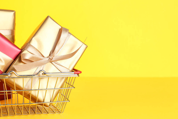Shopping basket with gift boxes on yellow background. Black Friday sale - Photo, Image